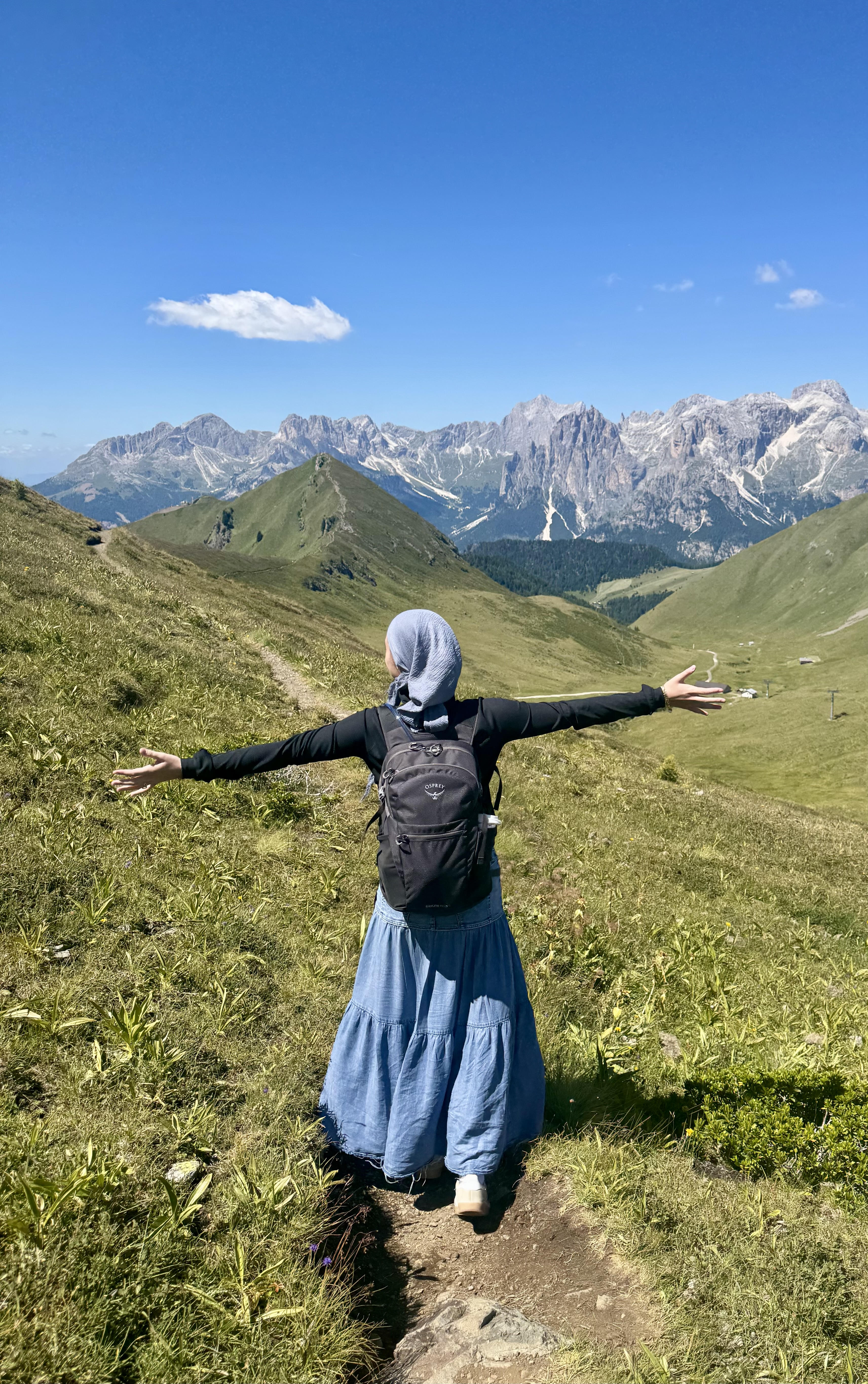 Avigail standing with arms outstretched before a mountain landscape